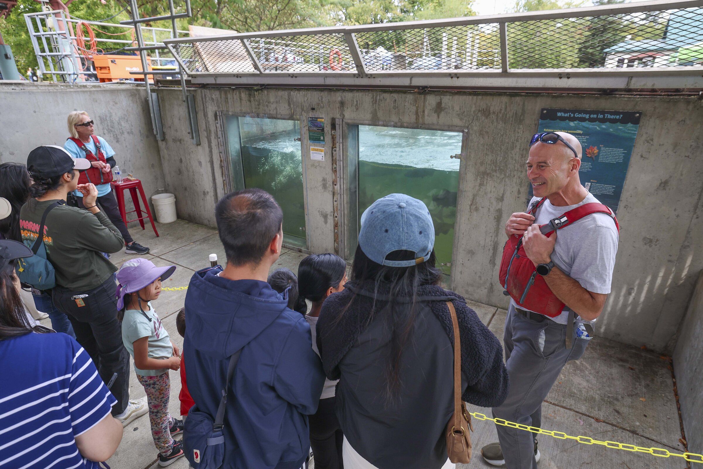 Volunteer Eric Streng, right, speaks with guests by a fish viewing area during the Salmon on Sunset Festival at Issaquah Salmon Hatchery in September. (Ivy Ceballo / The Seattle Times)