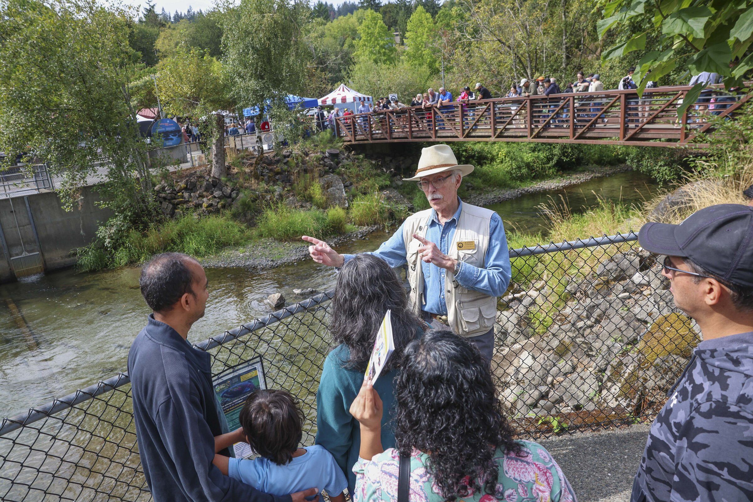 Randy Harrison, center, talks with visitors at the viewing bridge over Issaquah Creek about the journey salmon make. (Ivy Sebayo / The Seattle Times)