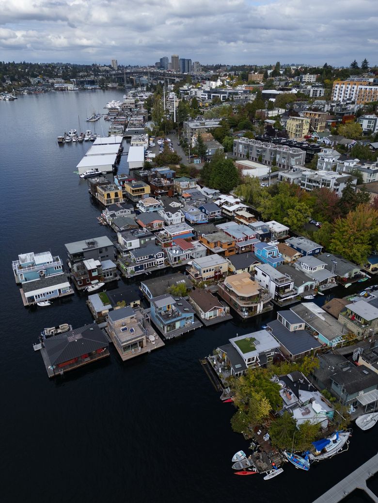 Some residents say the close proximity of neighbors and sharing a dock build camaraderie on Lake Union. A variety of floating homes in the Eastlake neighborhood are seen from the air. In the distance are high-rise buildings in the University District and the Ship Canal Bridge. (Ken Lambert / The Seattle Times)