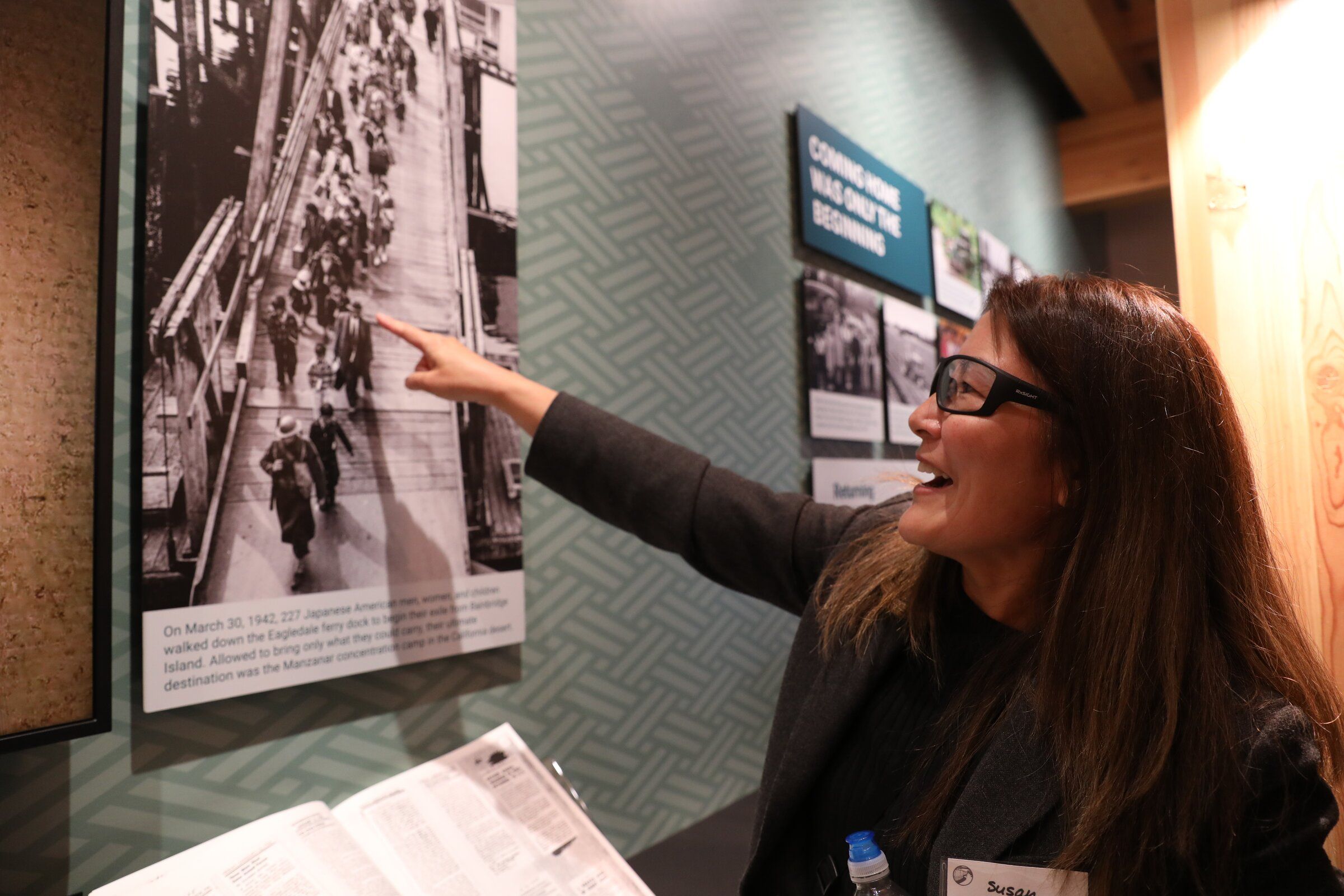 Seattle’s Susan Takemoto points to a picture of her dad, Billy Takemoto, as a child on the Bainbridge Island Eagledale ferry dock on March 30, 1942, on the way to ultimately being incarcerated at Manzanar incarceration camp. The Takemotos were at the opening of the Bainbridge Island Japanese American Exclusion Memorial visitor center on Sunday. (Naomi Ishisaka / The Seattle Times)