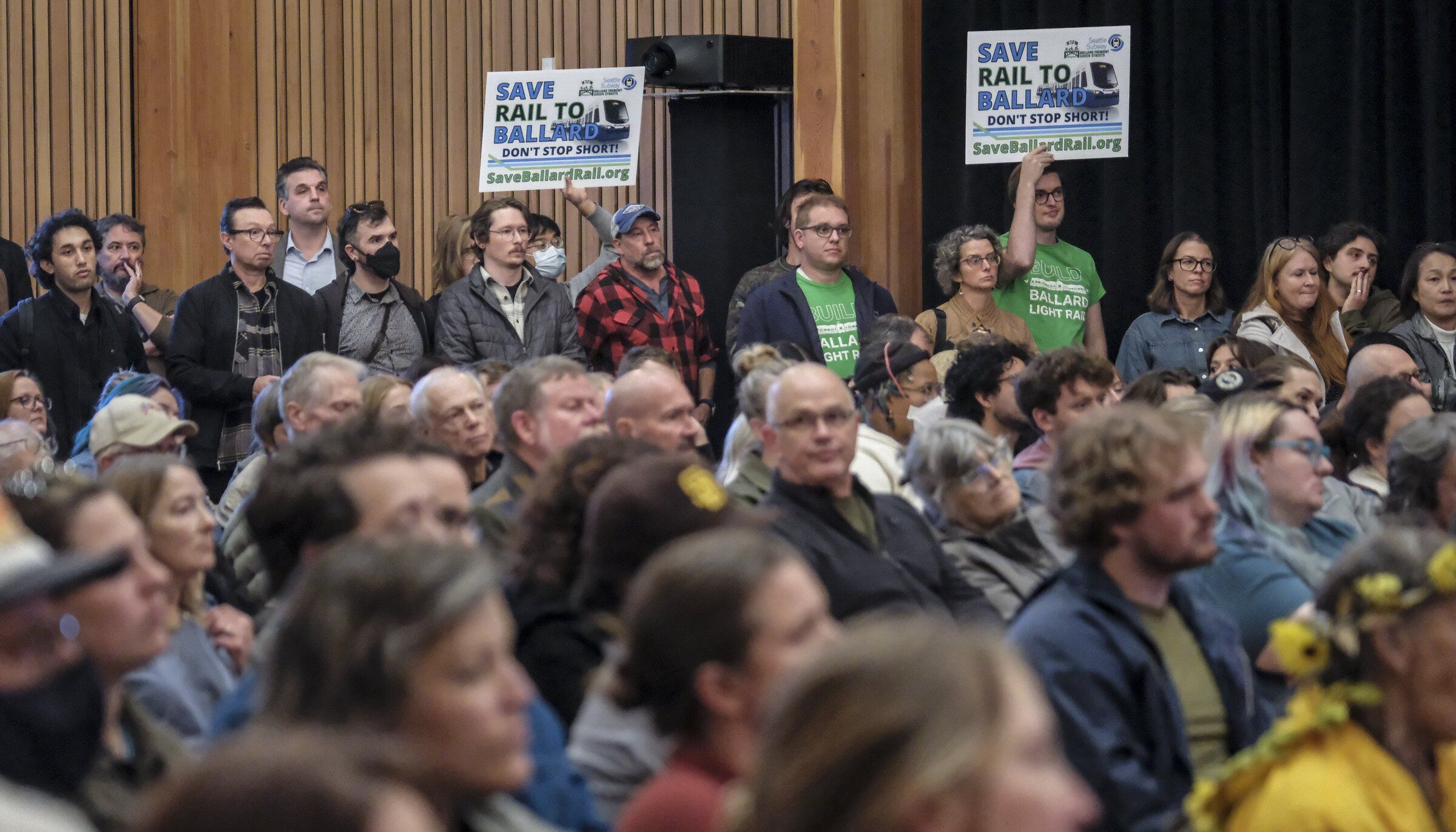 About 375 people, a few holding “Don’t Stop Short!’ signs, crowd into the National Nordic Museum to learn more about Sound Transit’s latest strategy for delivering long-delayed light rail to Ballard. (Dean Rutz / The Seattle Times)
