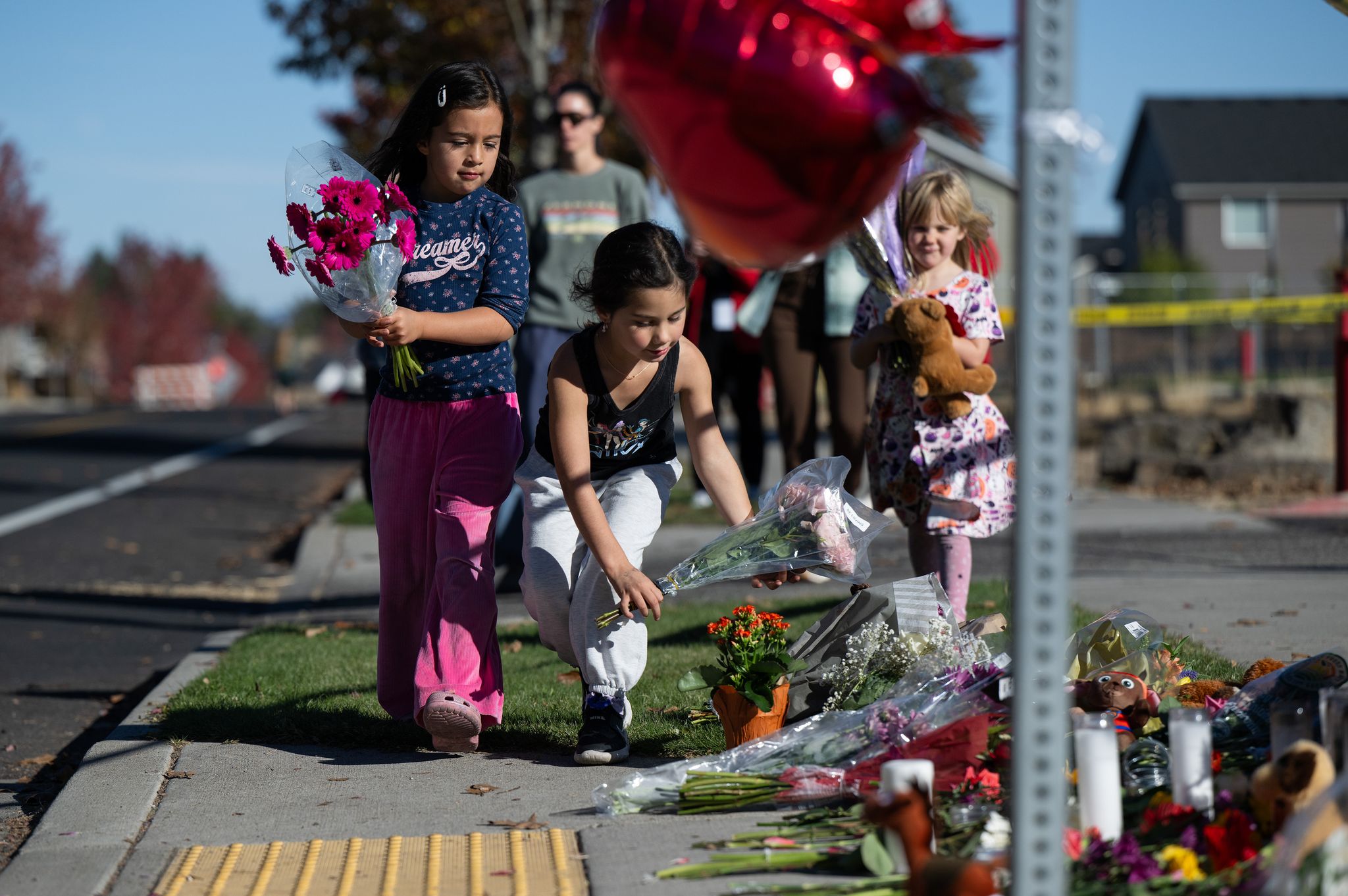 Children place flowers at a makeshift memorial outside Silver Rail Elementary in Bend, Ore., Friday, Oct. 16, a day after a deadly shooting. (Joe Kline / The Associated Press)